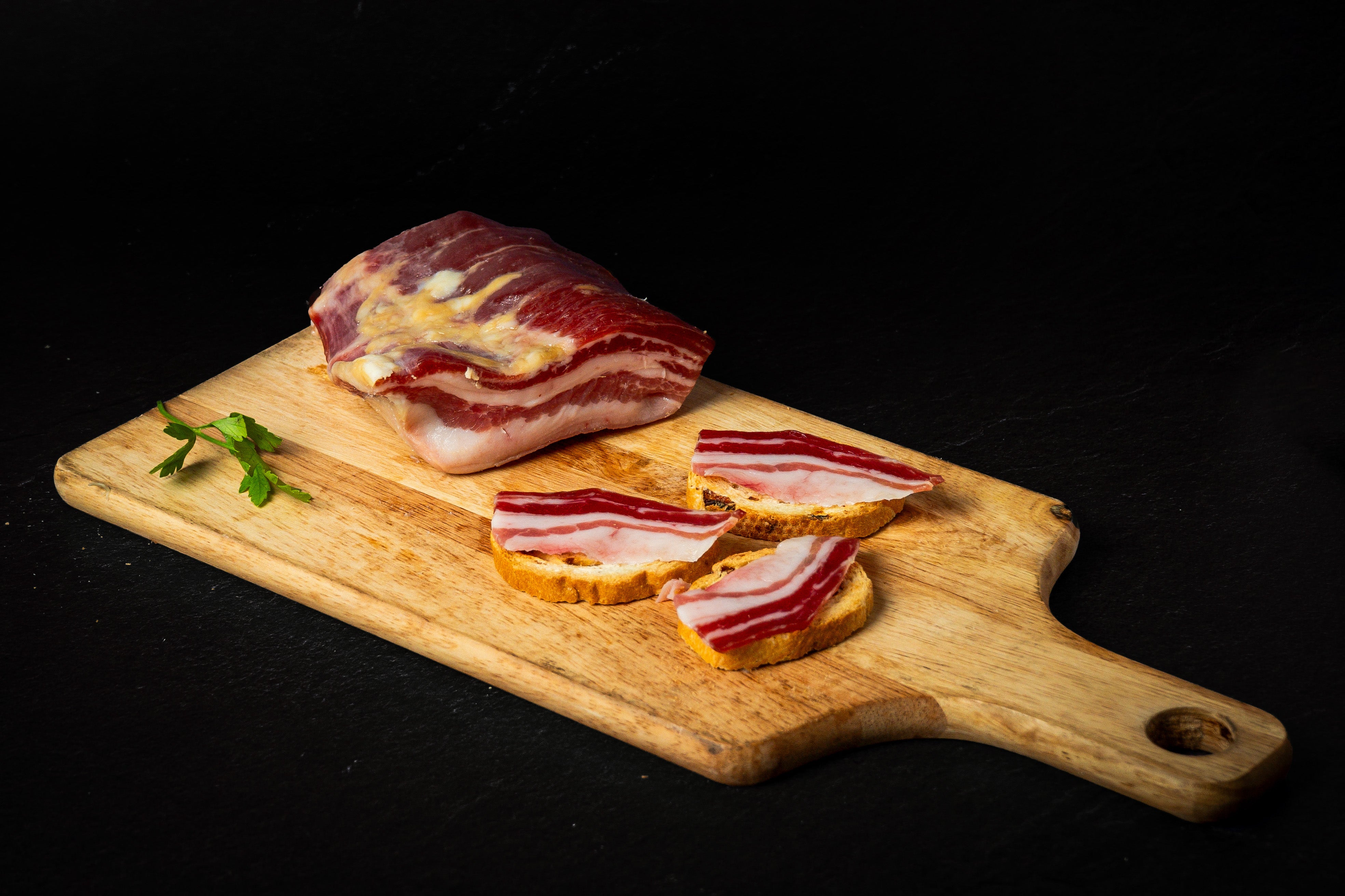 Panceta curada cortada en finos trozos sobre tostadas de pan.